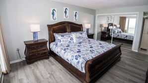 Un dormitorio con una cama de madera, dos mesitas de noche, un tocador, un espejo y una pared decorada con tres adornos de caballitos de mar.