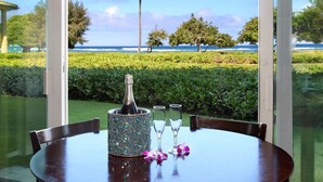 A table with a bottle of champagne, two glasses, and pink flowers.