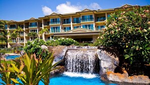 Un hotel con piscina, una cascada y un edificio grande con varios balcones.