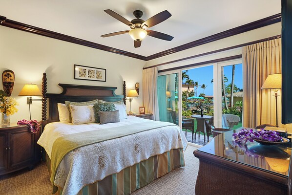 A hotel room with a large bed, a ceiling fan, a balcony with a view of palm trees, and a dining area with a table and chairs. - Waipouli Beach Resort Exquisite Grd Fr Pool View (Kapaa)