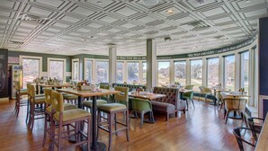 A spacious restaurant with high ceilings, large windows, and a variety of seating options including tables and chairs.