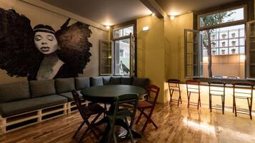 A modern interior with a round dining table, a sofa, and a large abstract mural on the wall.