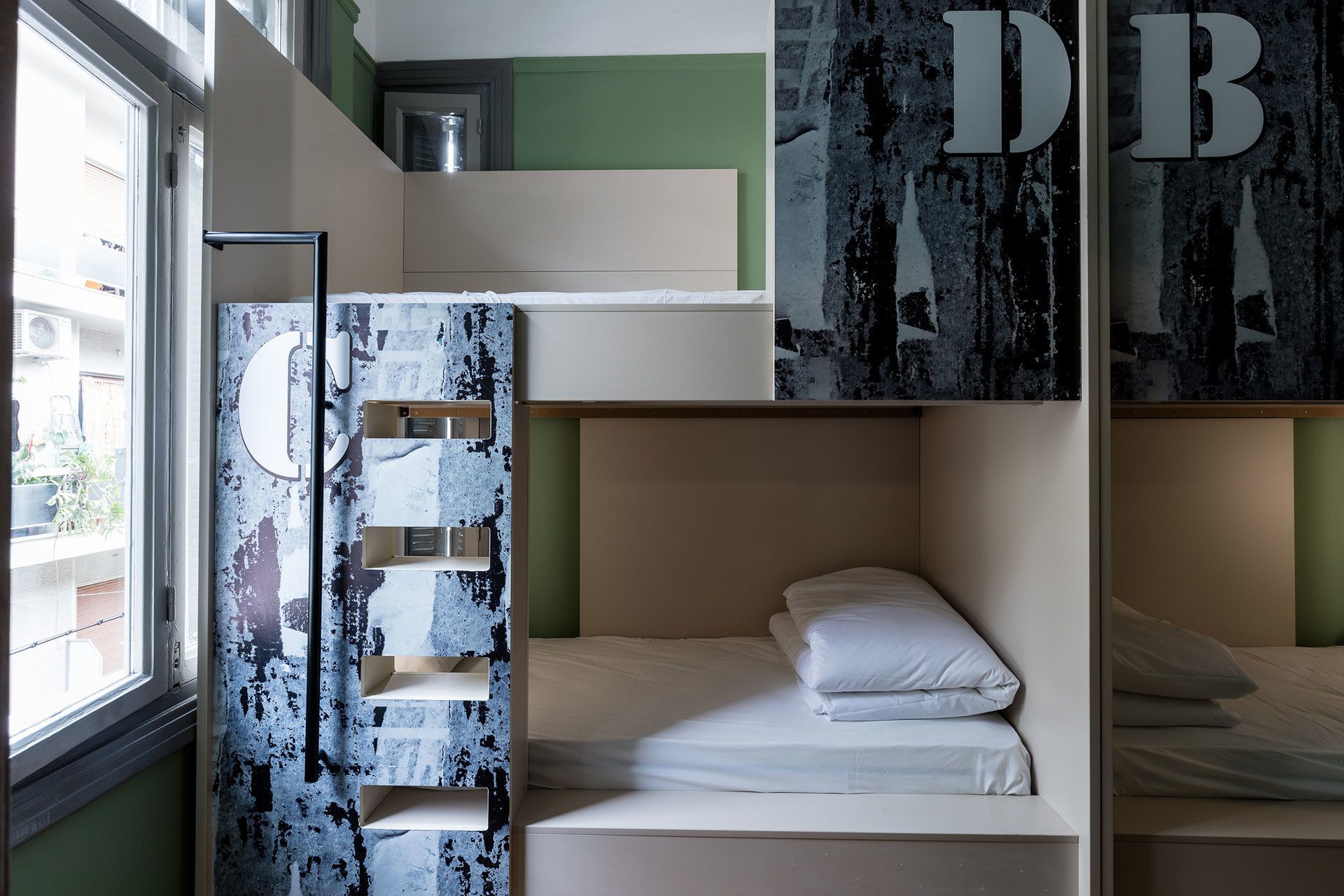 A bunk bed room with a window, a metal ladder, and a shelf with a mirror.