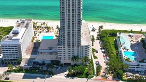 A tall hotel with a pool and beach view. - La Perla 5 star Condo  STR-00547 (Sunny Isles Beach)