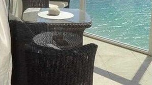 A balcony with wicker furniture and a view of the ocean. - La Perla 5 star Condo  STR-00547 (Sunny Isles Beach)