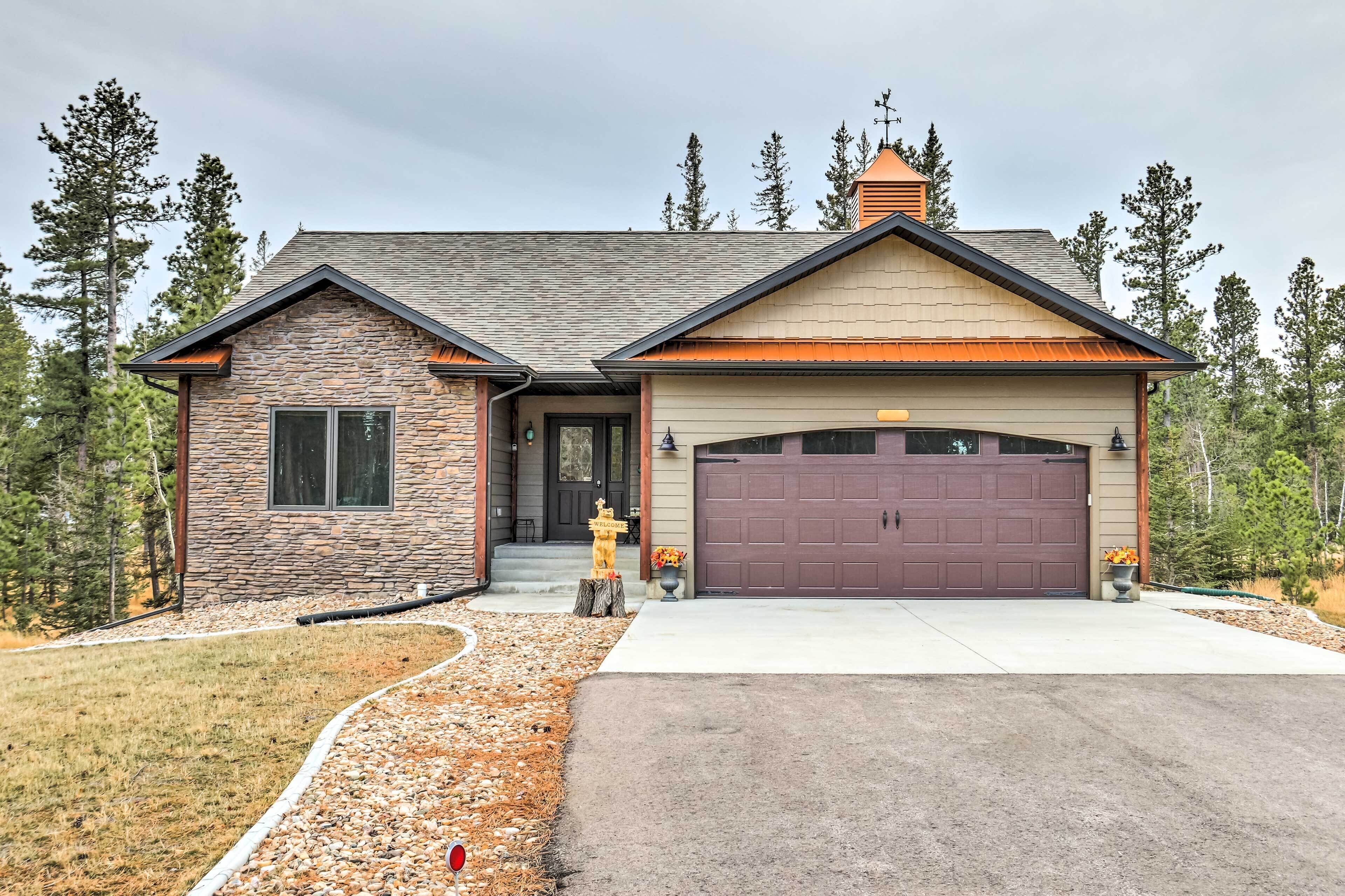 A modern two-story house with a stone facade, a large garage, and a well-maintained front yard.