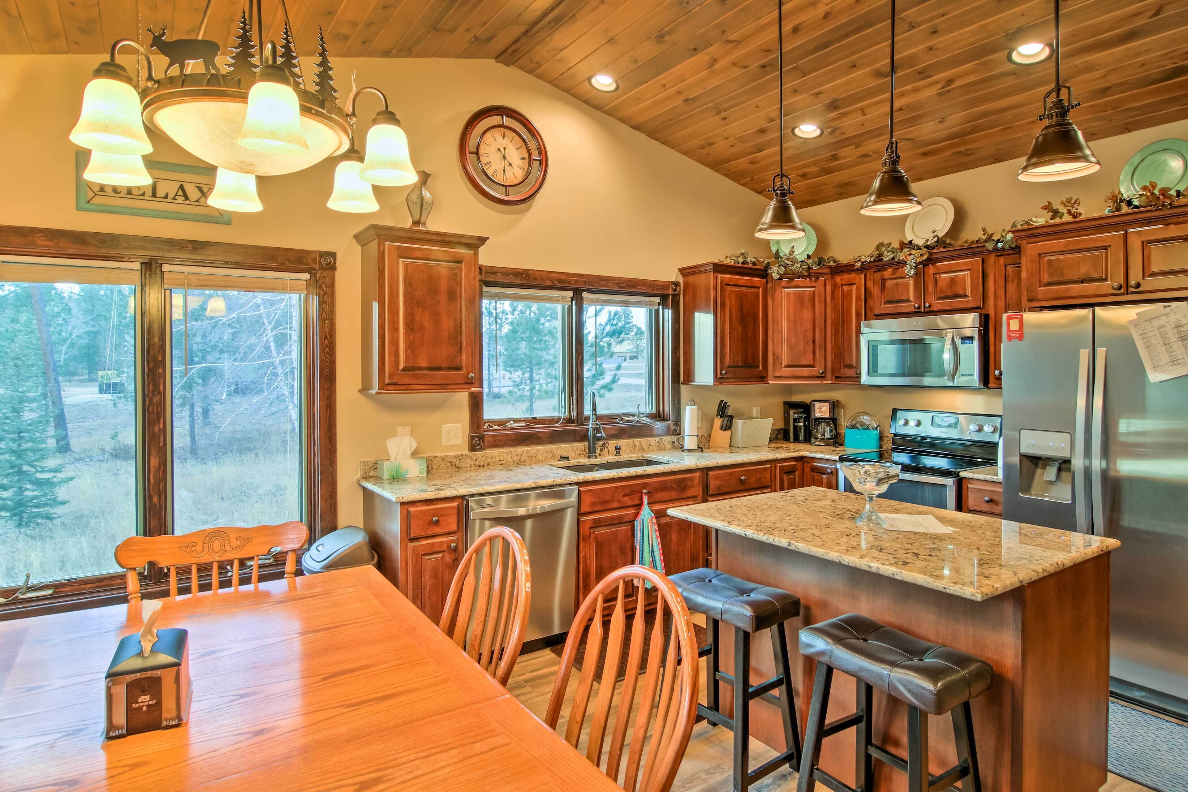 A modern kitchen with wooden cabinets, stainless steel appliances, and a large island with bar stools.