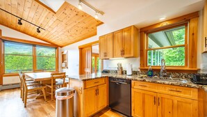 A modern kitchen with wooden cabinets, a stainless steel dishwasher, and a granite countertop.