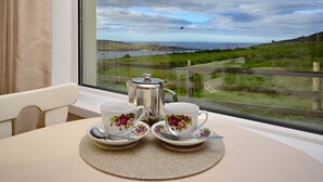 Ein Tisch mit zwei Tassen und einem Teekessel, vor einem Fenster mit Blick auf eine reizvolle Landschaft.