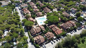 Vista aérea de una zona residencial con casas escalonadas, una piscina central y abundante vegetación.