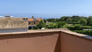 Un quartier résidentiel avec des toits recouverts de tuiles en terre cuite, un ciel dégagé et un parc arboré doté de sentiers.