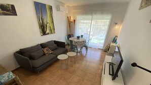 Un salon comprenant un canapé, deux petites tables, une table à manger avec des chaises et un escalier.