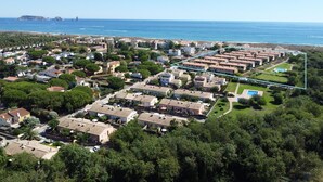 Vue aérienne d’un quartier résidentiel avec des maisons, une piscine et une plage en arrière-plan.