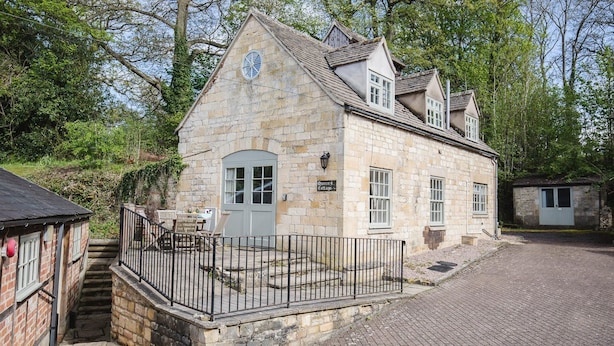 Ein Steinhäuschen mit einer kleinen Veranda und einem Schild, auf dem "Queen's Cottage" steht.