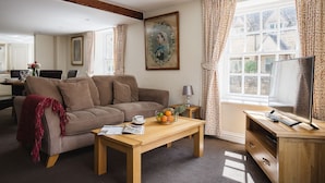 Ein gemütliches Wohnzimmer mit einer Couch, einem Couchtisch und einem Fernseher.