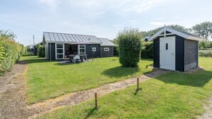 A modern house with a patio, a shed, and a well-maintained lawn.