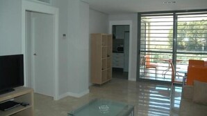 Amplia sala de estar con televisor de pantalla plana, un aparador de madera y puertas de vidrio corredizas que dan a un patio exterior con sillas.