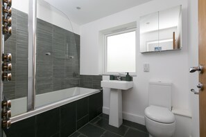 A modern bathroom with a glass-enclosed shower, a white sink, and a toilet.