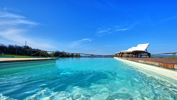 A clear blue pool with lounge chairs on the right side. - Borgo - Apartment with pool (Poggibonsi)