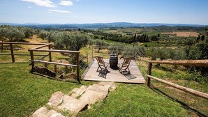 A wooden deck with two chairs and a barrel, overlooking a vineyard and distant hills. - Borgo - Apartment with pool (Poggibonsi)