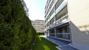 A modern building with a glass facade, a well-maintained lawn, and a clear sky.
