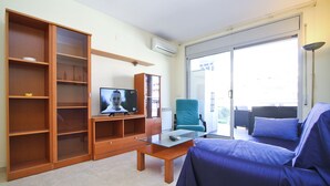 A living room with a television, a glass coffee table, a sofa, and a chair.