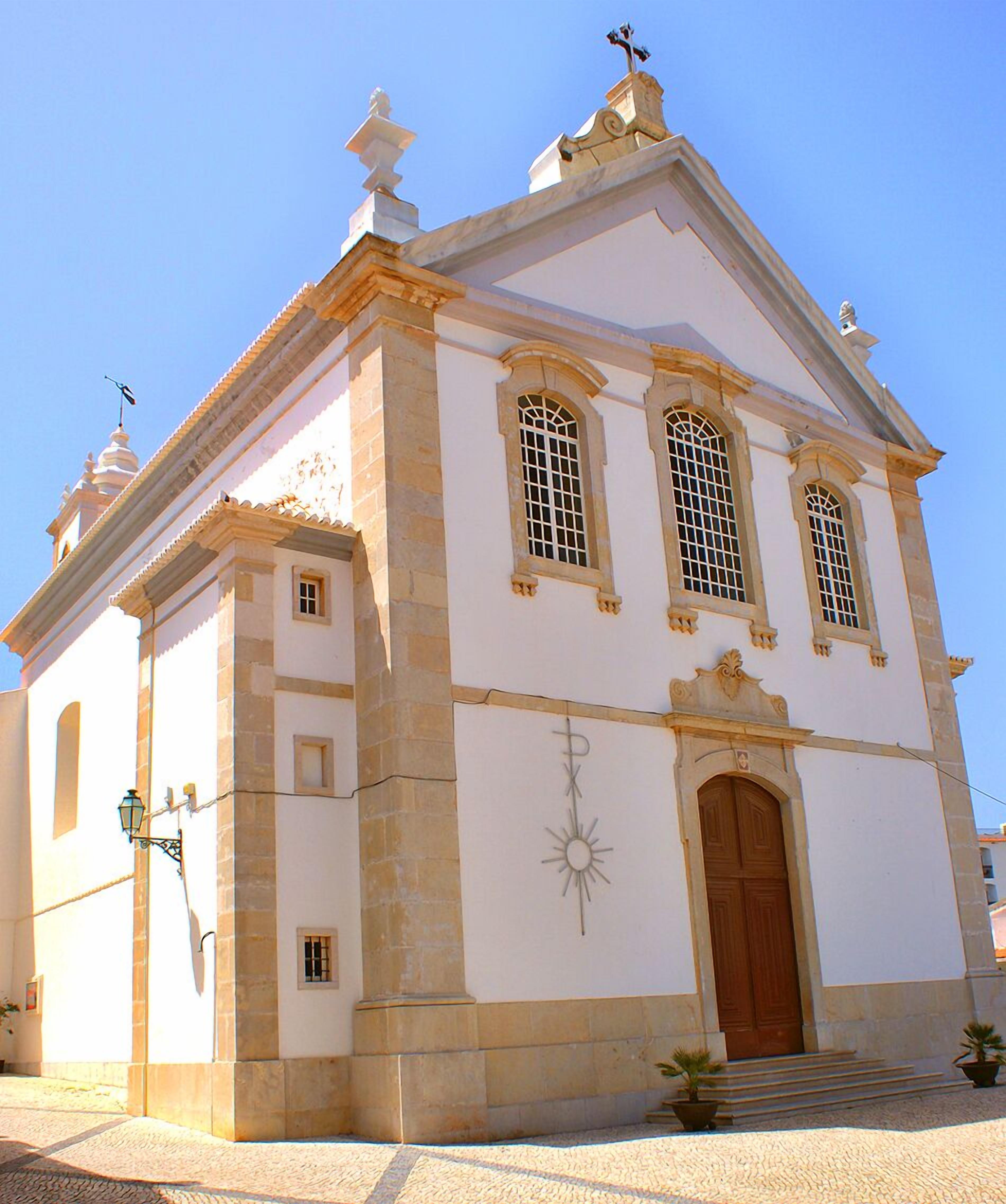 A white building with a central entrance, a cross on top, and a star decoration on the wall.