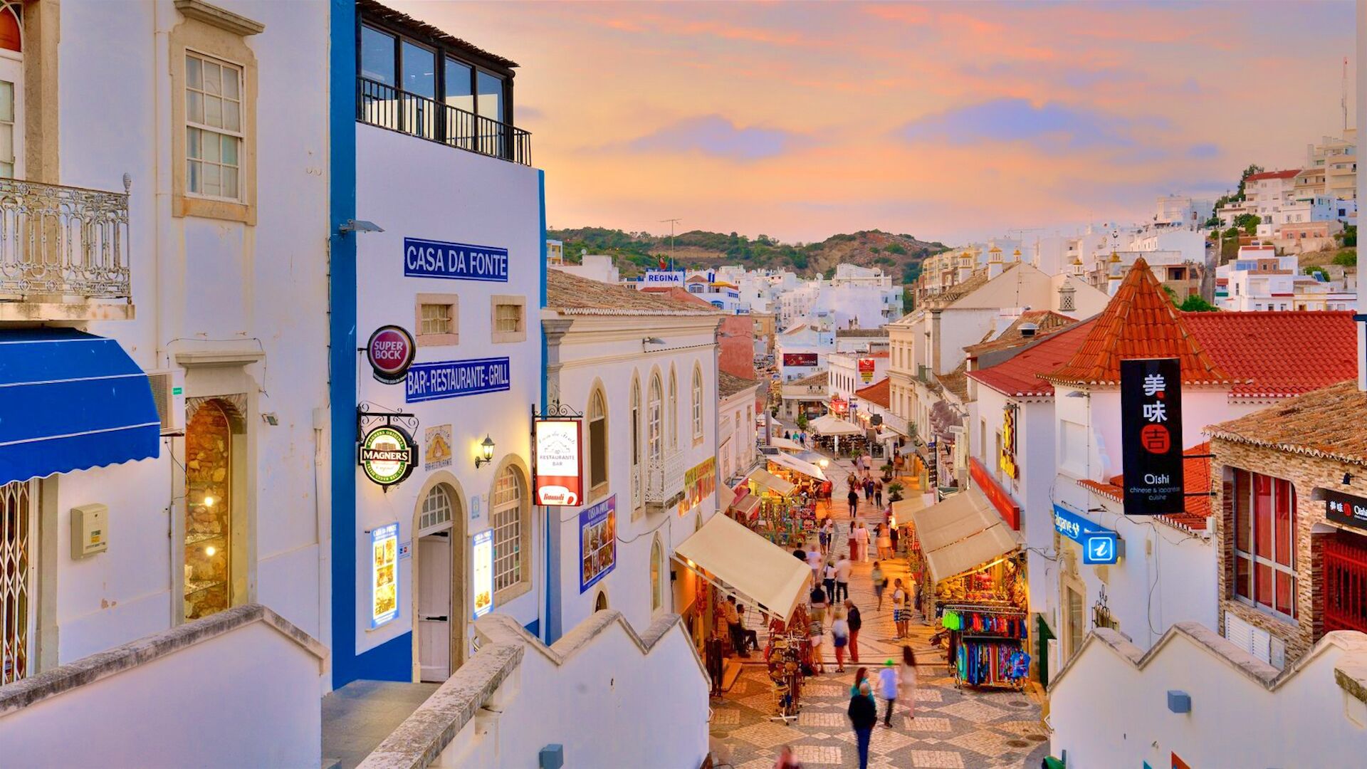 A bustling street scene in a historic town with narrow streets, traditional architecture, and various shops and restaurants.