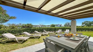 Une terrasse extérieure avec des chaises longues et une table préparée pour le petit-déjeuner.