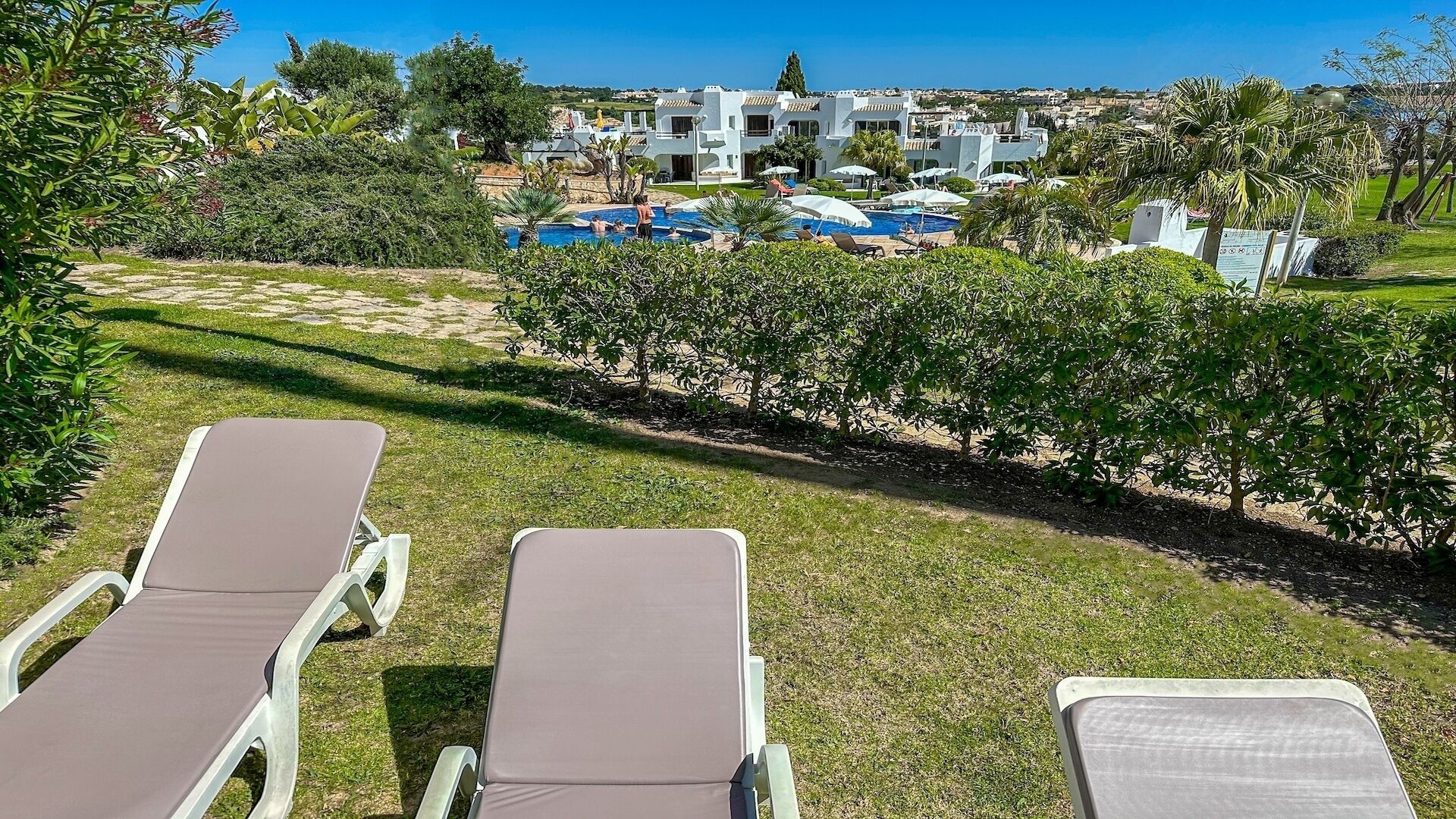 A resort with a pool area, lounge chairs, and a view of the ocean.