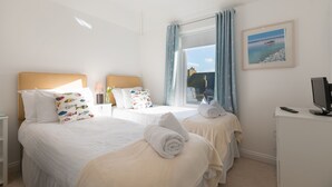 Habitación de hotel con dos camas, televisión y ventana con cortinas.