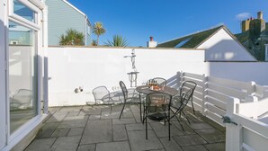 Un patio con una mesa y sillas, cerca blanca y cielo azul despejado.