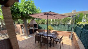 An outdoor patio with a brick barbecue, tiled flooring, and a table set for dining. - Daró 2D 167 - Community pool, corner house, A/C (Torroella de Montgri)