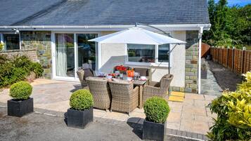 Enjoy a dining experience in a serene outdoor setting with a wicker table and chairs.