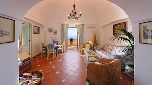 A cozy living room with a dining area, a chandelier, and a view of the sea. - Casa Elena - In the center of Praiano, Parking & Panoramic Hot tub (Praiano)