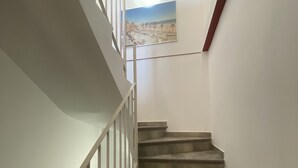 Una escalera con barandilla blanca y un cuadro de una playa en la pared.