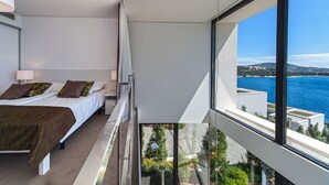 Et moderne soveværelse med balkon og udsigt over kysten.