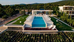 Et moderne resort med en stor pool, liggestole og udsigt over de omkringliggende bakker.