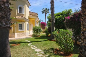 Stunning garden surrounds this charming residence, complete with a variety of plants and a vibrant flowering bush.