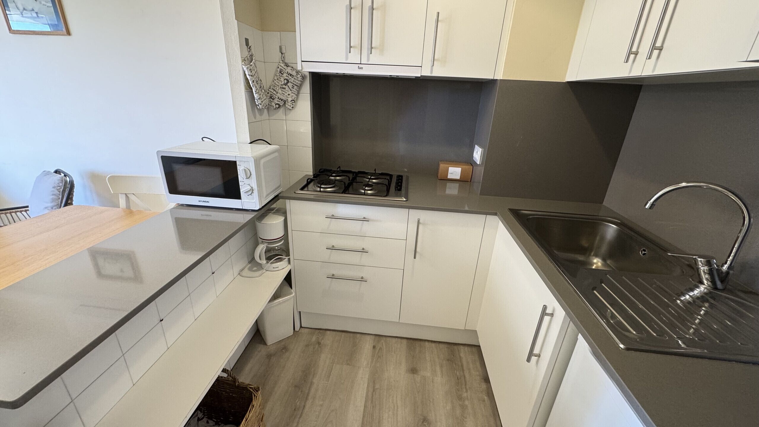 A modern kitchen with white cabinets, a microwave, a gas stove, and a stainless steel sink.