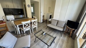 Een knus woongedeelte met kitchenette, eethoek, bank en televisie.