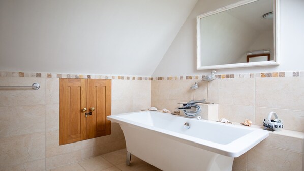 A bathroom with a freestanding bathtub, a wooden cabinet, and a tiled shower area. - Swallows Rest Cottage - sleeps 6 guests in 4 bedrooms (Broadway)