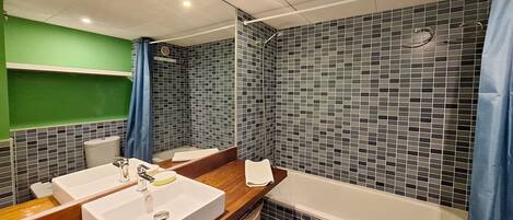 A modern bathroom with a large mirror, two sinks, a bathtub, and a shower with mosaic tiles.