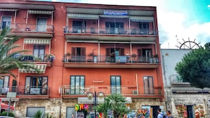 A multi-story building with balconies, a sign for a bed and breakfast, and a shop with colorful items displayed outside. - B&B L'Isola (Porto Cesareo)