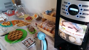 A coffee machine with a display screen advertising "L'ISOLA B&B" and a variety of food items on a table, including pastries and bread. - B&B L'Isola (Porto Cesareo)