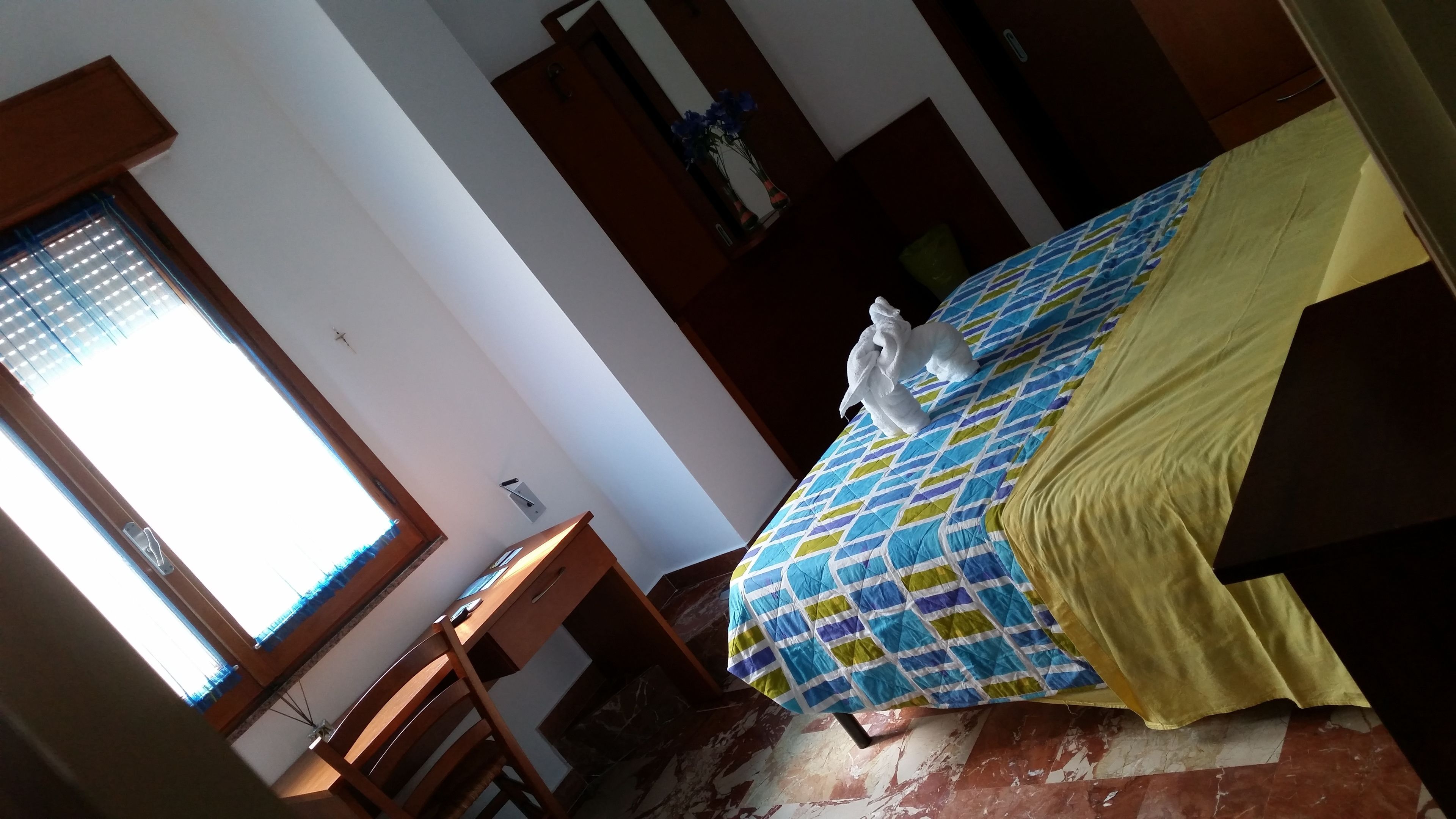 A room with a bed, a desk, and a window with blinds.