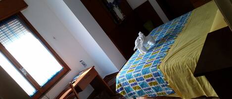 A room with a bed, a desk, and a window with blinds.