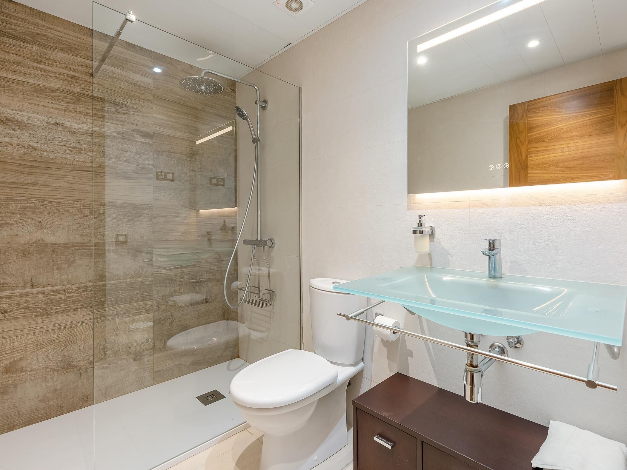 Une salle de bain moderne avec une douche à parois de verre, un lavabo en verre et un meuble-lavabo en bois.