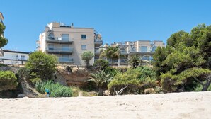 A coastal building with multiple balconies, surrounded by greenery and a sandy foreground. - Dream about front mediterranean sea views (Miami Platja)