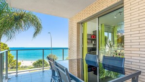 A balcony with a view of the sea, a glass door, and a table with chairs. - Dream about front mediterranean sea views (Miami Platja)